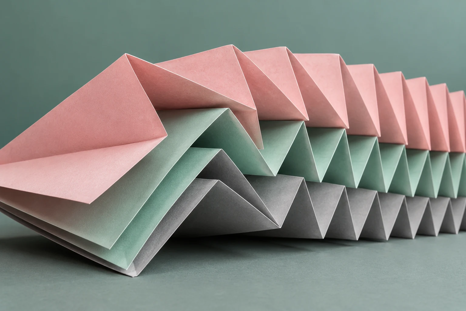 Papel plegado en acordeón rosa, menta y gris, fotografía ilustrativa generada con IA; no contiene informes, datos empresariales o certificados de cumplimiento reales.